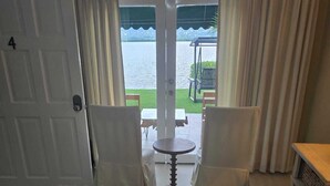 Ein Hotelzimmer mit Bett, einem kleinen Tisch und Blick auf ein Gewässer durch die Tür.