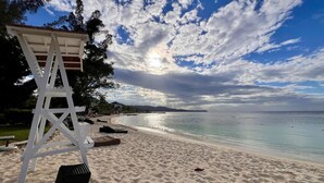 Ein Strand mit einem Rettungsturm, blauem Himmel und ruhiger See.