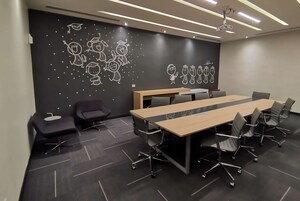 Un salón de conferencias con una larga mesa, sillas y un proyector.