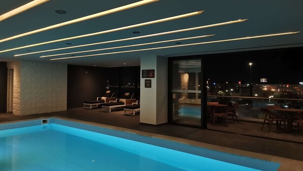 Un área de piscina interior moderna con una vista despejada del paisaje urbano de noche.