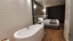 Un baño moderno con una bañera independiente, un banco de madera y un perchero visible.