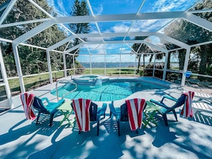Et overdækket udendørs swimmingpool med havudsigt, omgivet af liggestole og en pergola.