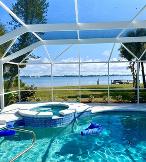A swimming pool with a clear view of the surrounding landscape, including a grassy area and a body of water. - SeaTurtle đ˘Bayfront w/ heated pool, steps to Beach, Sleeps 10, Petsđž (Englewood)
