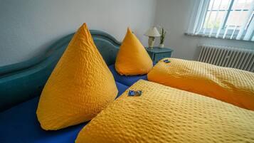 Un letto con biancheria azzurra e tre cuscini gialli.