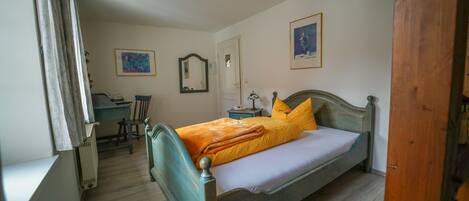 A bedroom with a bed, a desk, and a chair.