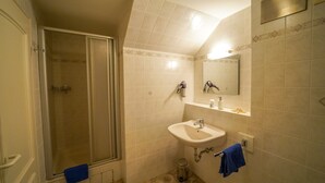 Un baño con ducha, lavabo y espejo.