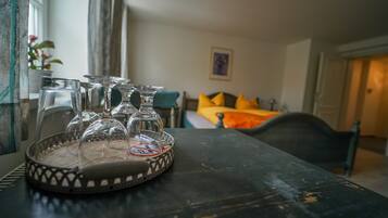 A room with a bed, a table with a tray of wine glasses, and a window with curtains.