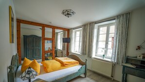 Un dormitorio con una cama de madera, un escritorio, una silla, un espejo y una ventana con cortinas.