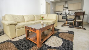 A living room with a beige sofa, a wooden coffee table, and a kitchen in the background. - No 5 Central by Brighton Holiday Lets (Brighton)