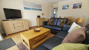 A living room with a sofa, wooden coffee table, and a television on a cabinet.