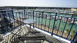 A balcony with a table and chairs overlooking a marina with numerous boats.