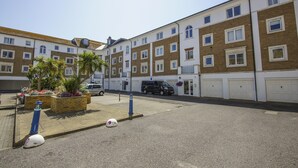A multi-story residential building with a parking area in front.