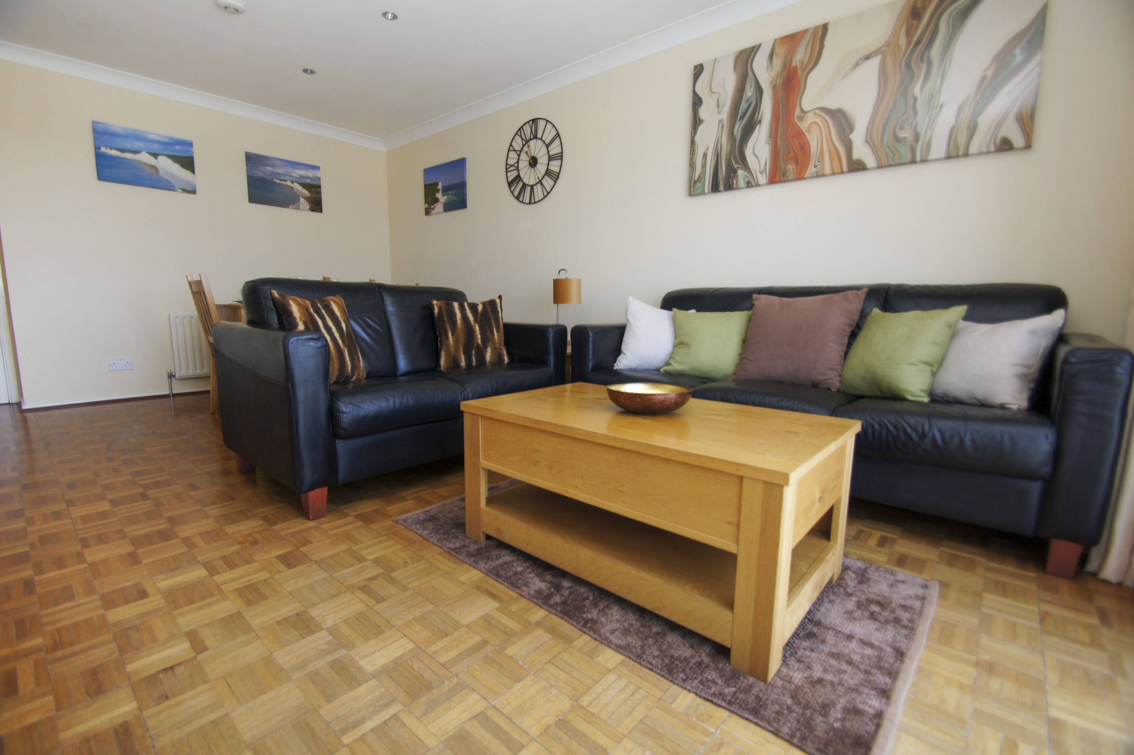A living room with two sofas, a coffee table, and a clock on the wall.