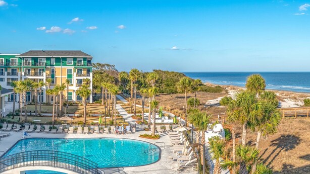 A resort with a swimming pool, palm trees, and a view of the ocean. - Residence Inn by Marriott Jekyll Island (Jekyll Island)