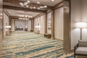 Un pasillo de hotel con alfombra estampada, una recepción y una zona de estar con lámpara.