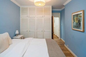 Une chambre à coucher avec un lit, une table de chevet, une armoire et un tableau encadré au mur.