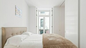 A bedroom with a bed, a window, and a door leading to a balcony. - Bright and Spacious 1 Bed Apartment near Baixa (Lisboa)