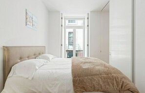Une chambre à coucher avec un lit, une fenêtre et une porte donnant sur un balcon.