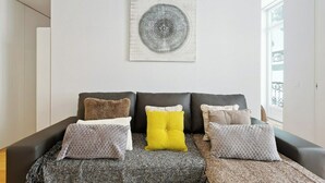 A living room with a sofa set, a patterned rug, and a wall-mounted artwork. - Bright and Spacious 1 Bed Apartment near Baixa (Lisboa)