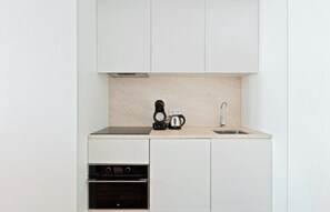 Uma cozinha compacta com forno embutido, cafeteira e pia.