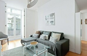 Ein modernes Wohnzimmer mit einem Glastisch, einer dunkelbraunen Ledersofa und Sitzkissen mit Muster, sowie einem Wandbild.