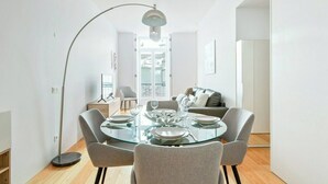 Ein moderner Essbereich mit einem Glastisch, grau gepolsterten Stühlen und einer Stehlampe.