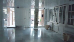 En rymlig entréhall med högt i tak, stora fönster och ett rent, välpolerat golv.