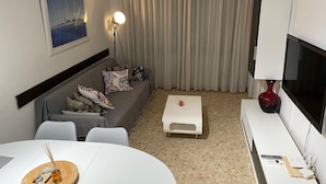 Ett modernt vardagsrum med en soffa, ett soffbord, en tv och en tavla på väggen.