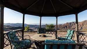 A covered outdoor seating area with a fire pit, two chairs, and a table. - Amazing Retreat with Unbelievable Views in Malibu (Malibu)
