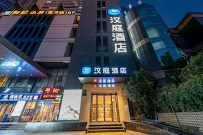 A hotel with a prominent sign, a modern facade, and a staircase leading to the entrance.