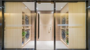 Ett modernt hotellrum med en skjutdörr som leder till badrummet. Rummet har hyllor i trä där handdukar och toalettartiklar är prydligt uppställda.