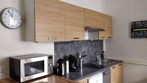 Eine moderne Küche mit Holzausstattung, einer Edelstahl-Mikrowelle, einer Kaffeemaschine und einem Spülbecken.