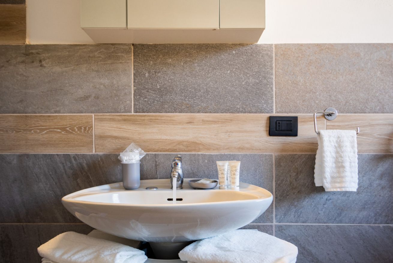Een badkamer met een witte wastafel, een handdoekhouder en een kastje boven de wastafel.