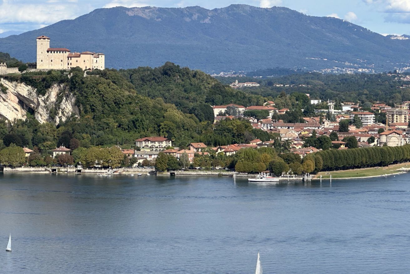 A castle on a hill overlooking a town by a lake.
