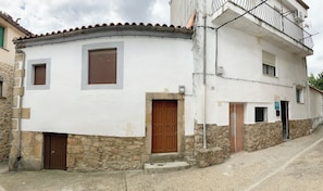 Un edificio de dos pisos con fachada blanca, base de piedra y puerta marrón.