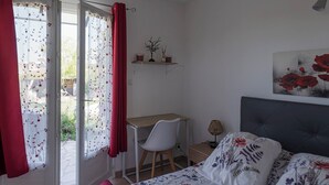 Een slaapkamer met een bed, een bureau en een stoel. Er is een raam met gordijnen en uitzicht op buiten.