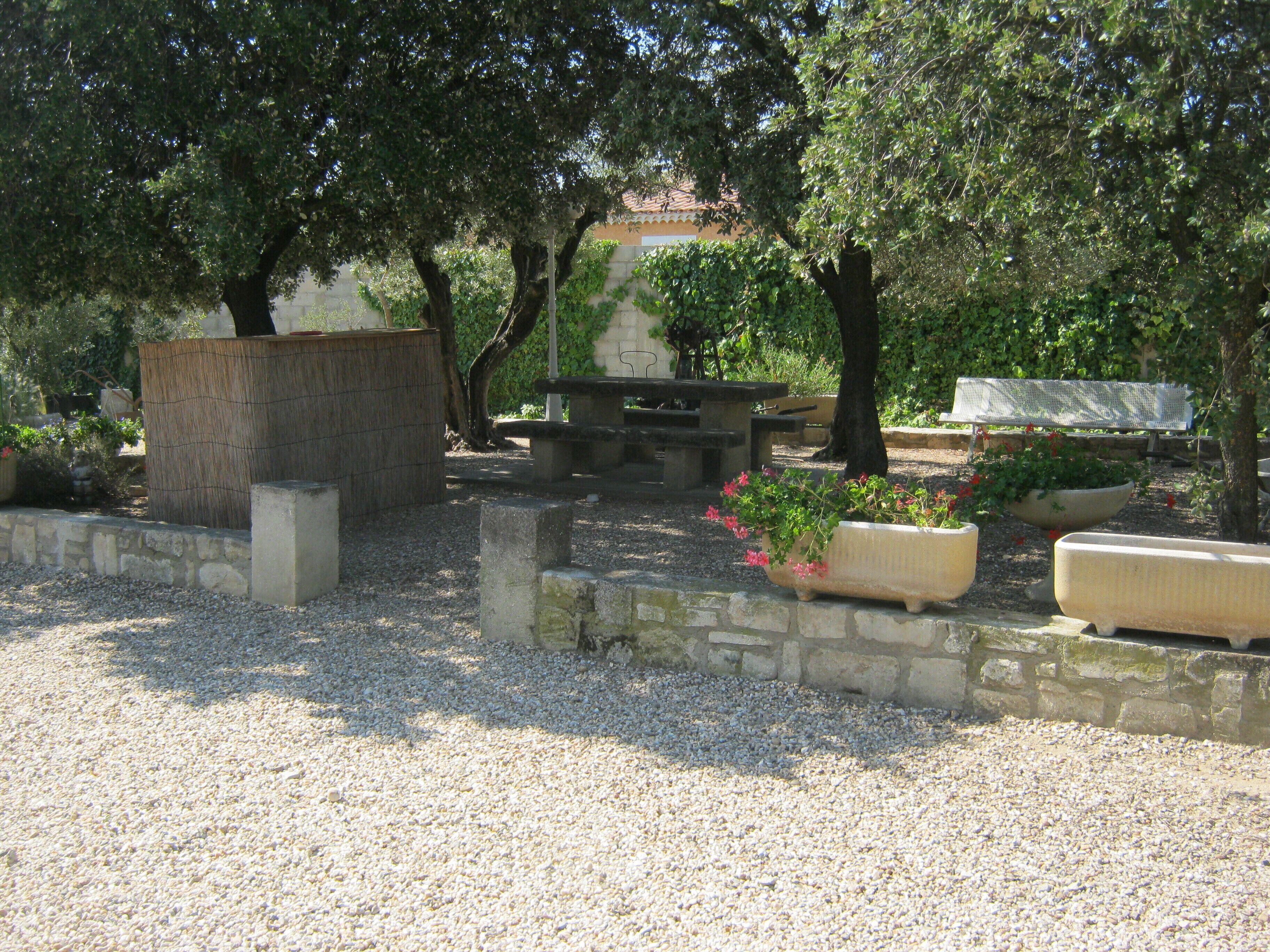 Un jardín con bancos de piedra, una pérgola y plantas en macetas.