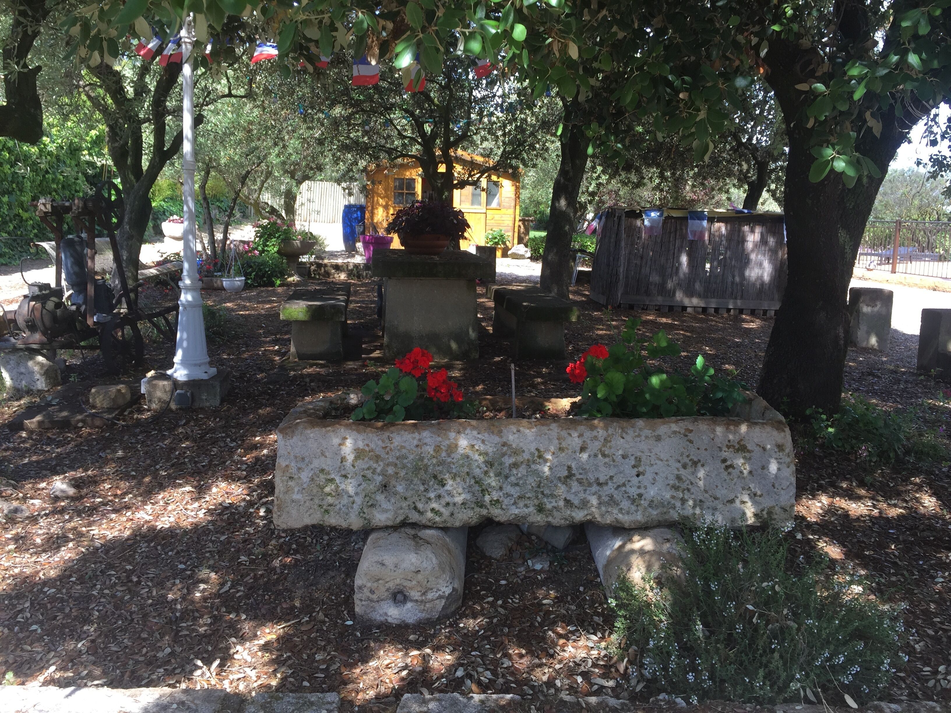 A cemetery with headstones, a wooden structure, and a bench with red flowers.
