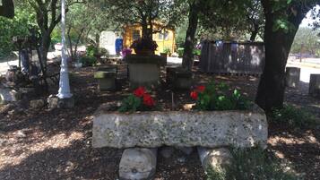 A cemetery with headstones, a wooden structure, and a bench with red flowers.