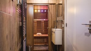 Een smalle gang die leidt naar een houten kast met een ingebouwde bank, een radiator en een klein wastafeltje.