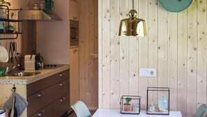 Een keuken met houten lambrisering, een wit aanrecht en een hangende messing hanglamp.