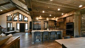 Un'ampia cucina con una grande isola, mobili in legno e una parete decorata con pietra.