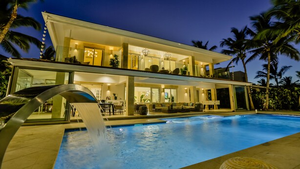 A modern two-story house with a swimming pool, outdoor seating, and a waterfall feature. - Luxury Sunshine II. villa with SEA & GOLF VIEW, pool heated, CHEF & staff incl. (Punta Cana)