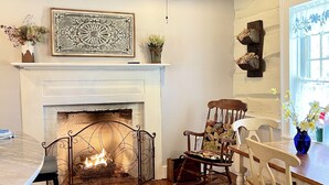 A cozy room with a fireplace, wooden flooring, a dining table, and a ceiling fan. - Charmingly renovated historic Canal House on C&O along Potomac close to Antietam (Sharpsburg)