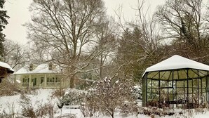 Two snow-covered Adirondack chairs in a snowy garden with a greenhouse and a house in the background. - Charmingly renovated historic Canal House on C&O along Potomac close to Antietam (Sharpsburg)