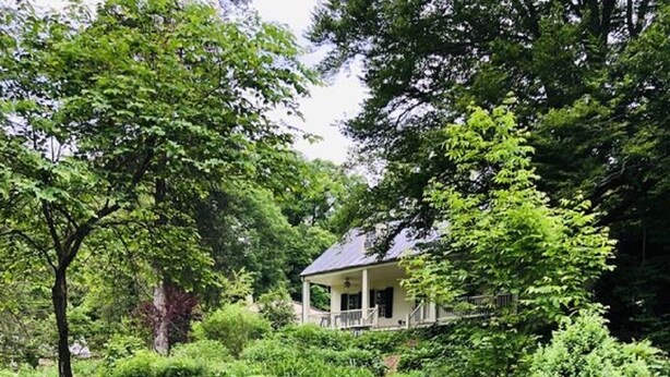A lush garden with a variety of flowering plants and a house with a porch. - Charmingly renovated historic Canal House on C&O along Potomac close to Antietam (Sharpsburg)