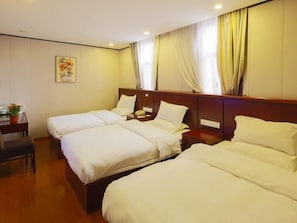 Une chambre d’hôtel avec deux lits simples, un bureau avec une chaise, un téléphone et une petite table avec une plante.