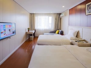 Habitación de hotel con dos camas, un escritorio, un televisor y una ventana con cortinas.