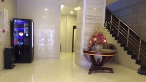 A hotel lobby with a StarInco machine, a round table with a vase of flowers, and a staircase. - Greentree Alliance Shanghai Railway Station Qiujiang Road Hotel (Shanghai)