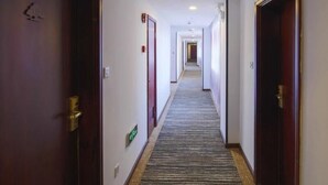 A hotel corridor with wooden doors, a carpeted floor, and a long hallway leading to a room. - Greentree Alliance Shanghai Railway Station Qiujiang Road Hotel (Shanghai)
